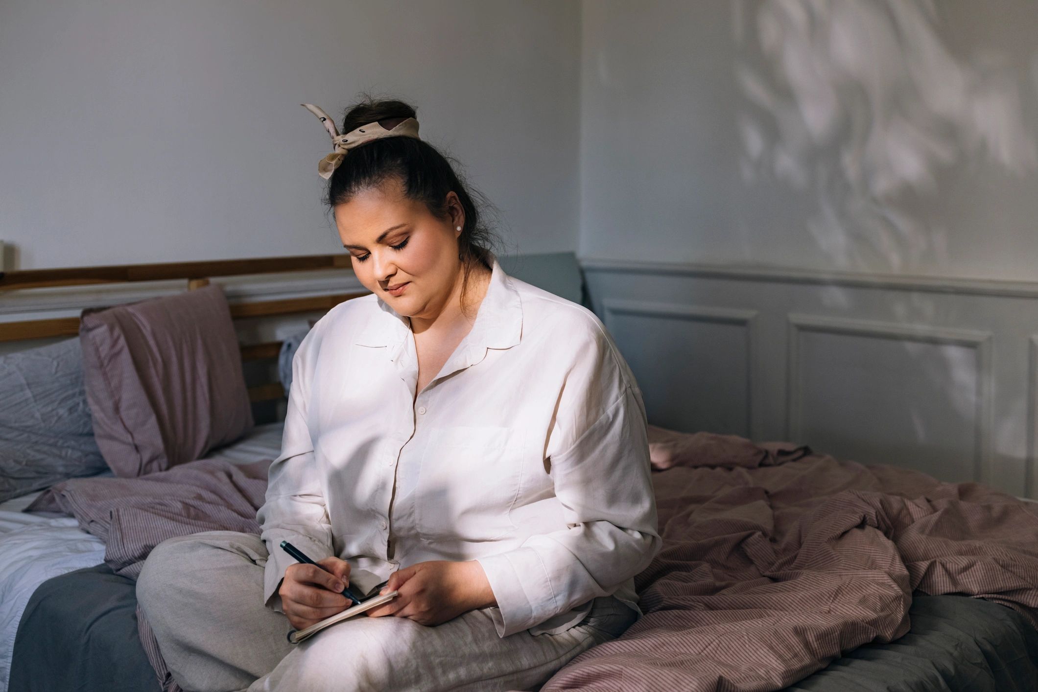 Woman journaling in warm light, reflecting and planning