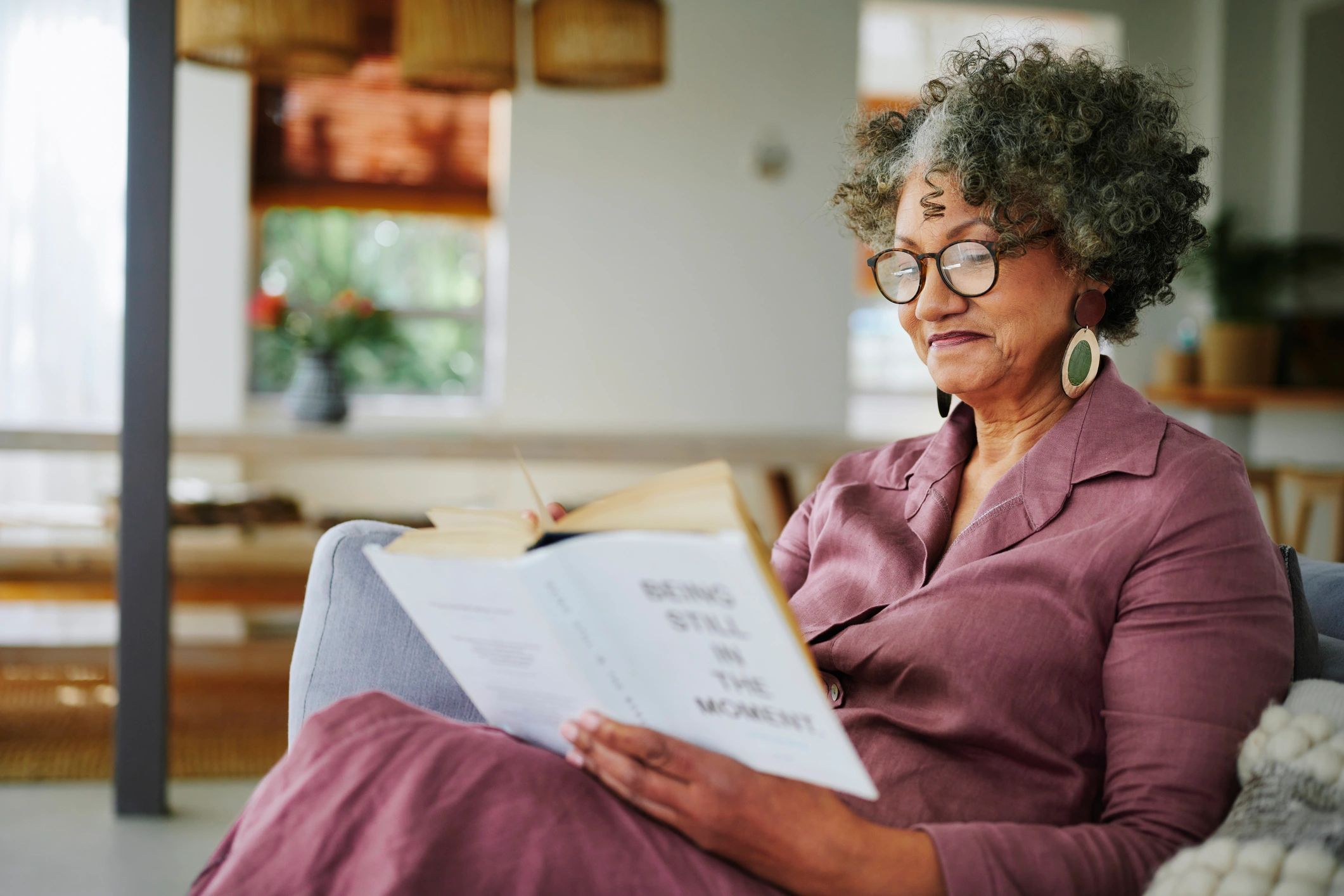 Woman relaxing on a sofa reading a self-help book