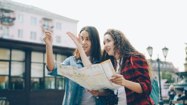 Two smiling women exploring a new city with a map