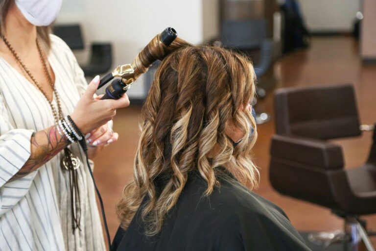 Woman getting her hair curled and styled at a salon