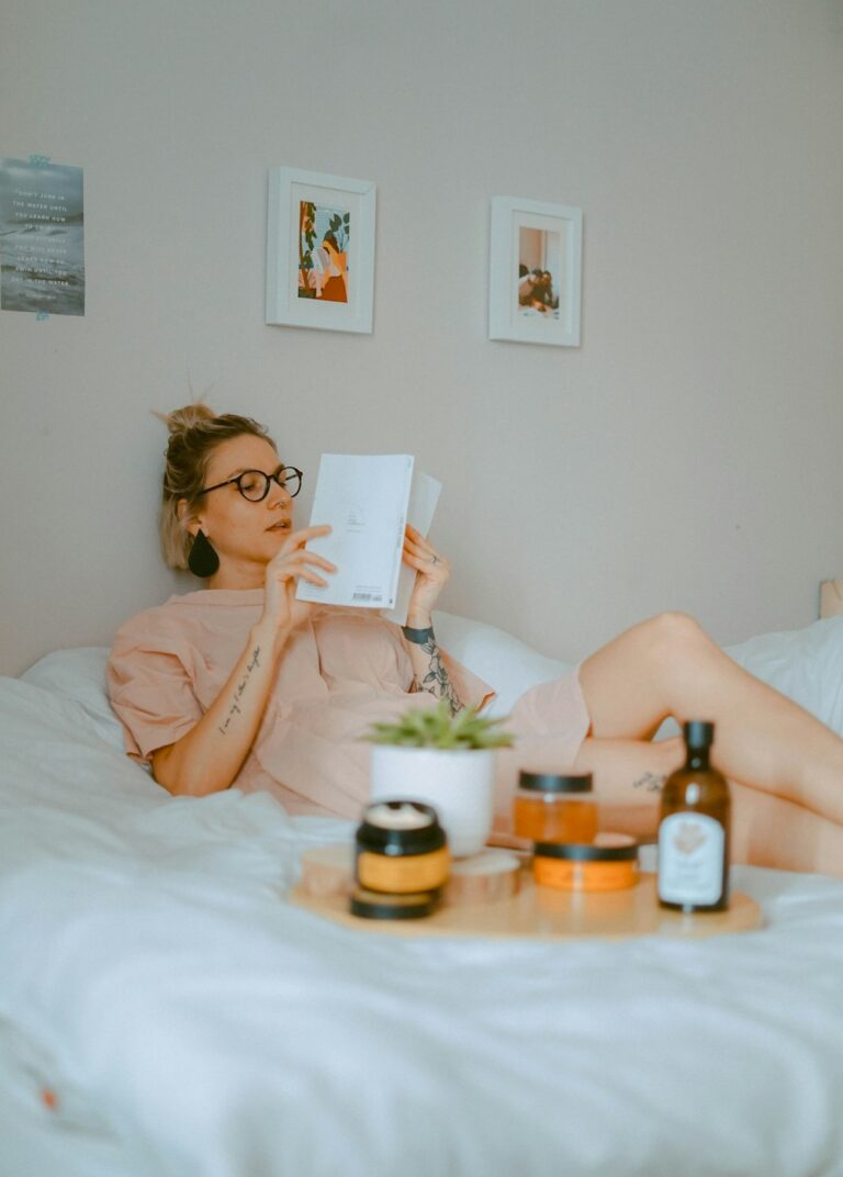 Woman relaxing in bed with self-care products